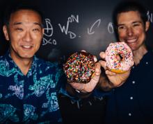 Ken Ono y John Duncan, de la Universidad Emory, posan muy sonrientes con unos donuts de colores espolvoreados